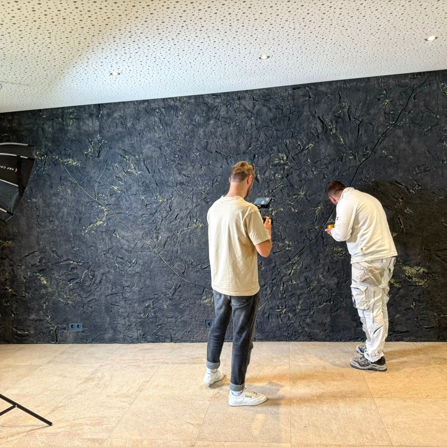 Zwei Handwerker besprechen eine Wandoberfläche