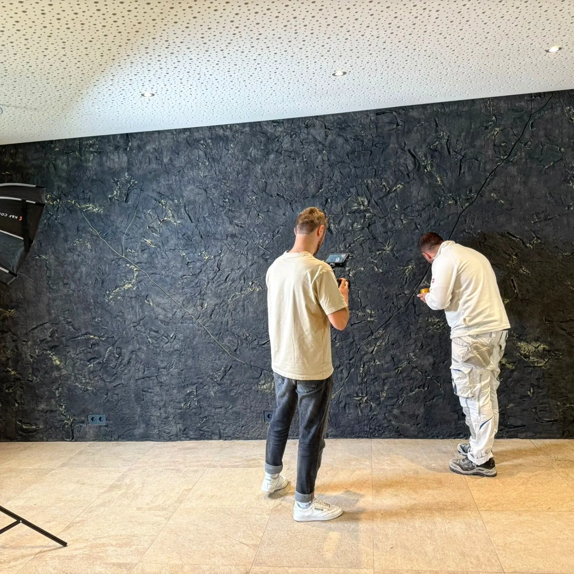 Zwei Handwerker besprechen eine Wandoberfläche
